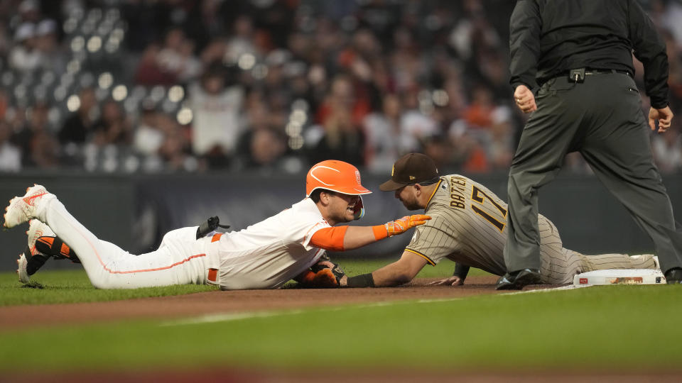 San Francisco Giants' J.D. Davis, left, is tagged out trying to advance to third base on a double by San Diego Padres third baseman Matthew Batten during the first inning of a baseball game in San Francisco, Tuesday, Sept. 26, 2023. (AP Photo/Jeff Chiu)