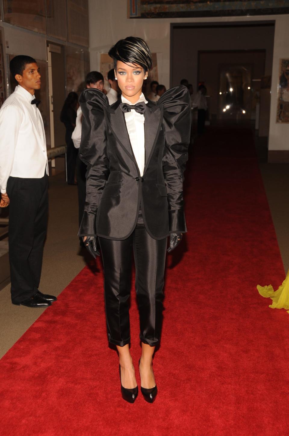 Rihanna at the 2009 Met Gala wearing a black tuxedo with cropped pants and butterfly shoulders.