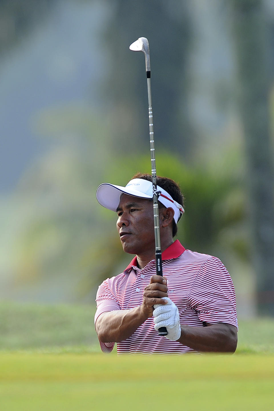 Thailand's Thongchai Jaidee watches his shot from the rough on the first hole during the first round of the Eurasia Cup golf tournament at the Glenmarie Golf and Country Club in Subang, Malaysia, Thursday, March 27, 2014. (AP Photo/Joshua Paul)