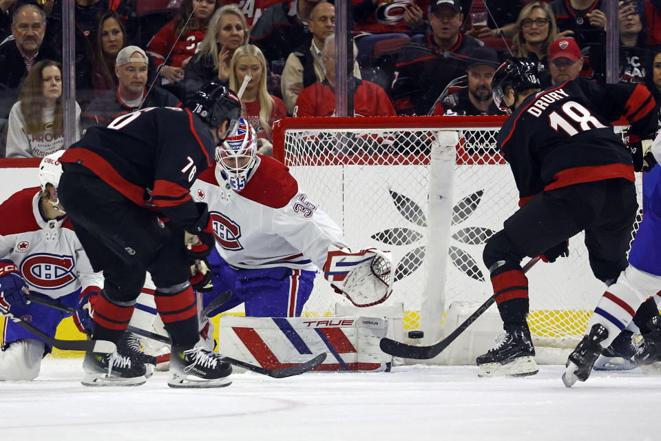 Carolina Hurricanes' Brady Skjei (76) slips the puck past Montreal Canadiens goaltender Sam Montembeault (35) with Hurricanes' Jack Drury (18) looking on during the first period of an NHL hockey game in Raleigh, N.C., Thursday, March 7, 2024. (AP Photo/Karl B DeBlaker)