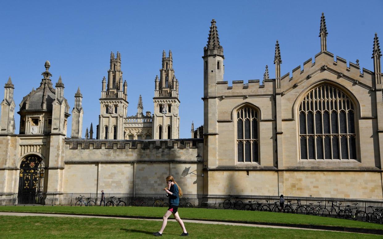 A student walks across a lawn in front of All Souls College, Oxford University -  TOBY MELVILLE/REUTERS