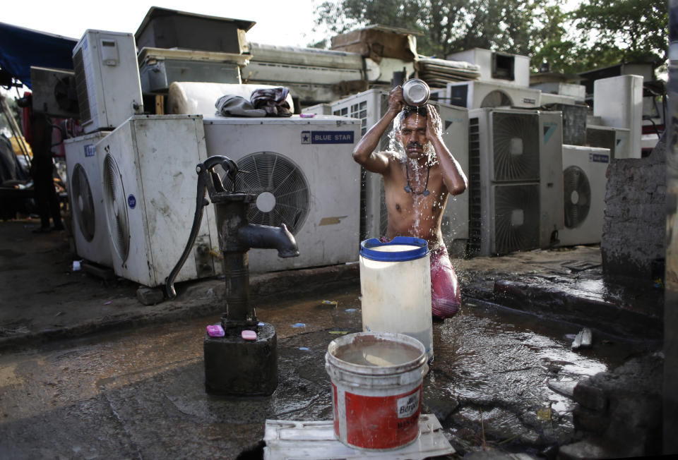 FILE - A migrant daily wage worker bathes at a public well pump on a hot morning in New Delhi, India, May 17, 2016. A new study Thursday, May 18, 2023, finds the natural burst of El Nino warming that changes weather worldwide is far costlier with longer-lasting expenses than experts had thought, averaging trillions of dollars in damage. (AP Photo/Altaf Qadri, File)