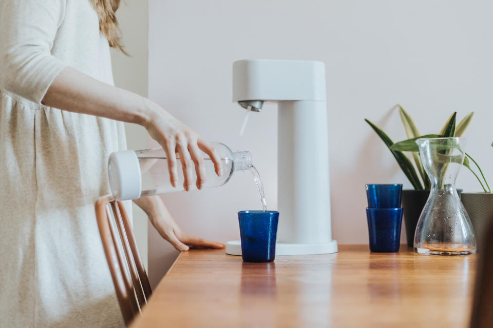 Close up of woman making sparkling water at home.