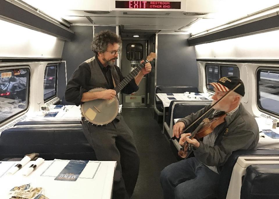 In this photo taken Friday, Jan. 20, 2017, photo, Paul Draper, 59, of Voorheesville, N.Y., left, and 63-year-old Mike Jarboe of Clifton Park, play music on the train north of New York City. AP Tampa correspondent Tamara Lush spent 15 days traveling via train across the U.S. as part of Amtrak's residency program, designed for creative professionals to spend time writing on the rails. She spoke with dozens of people _ fellow travelers, friends and family waiting for loved one at stations, train workers _ and filed occasional dispatches for the Tales on a Train project. (AP Photo/Tamara Lush)