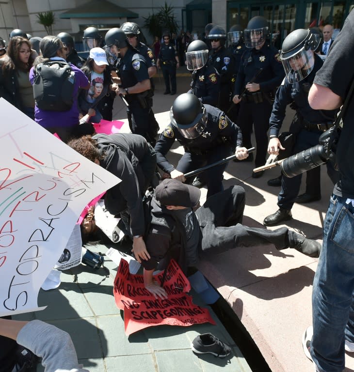 A protester takes a hit from a police officer after a mob forced their way past a barricade at the hotel where US Republican presidential candidate Donald Trump was speaking in Burlingame, California on April 29, 2016