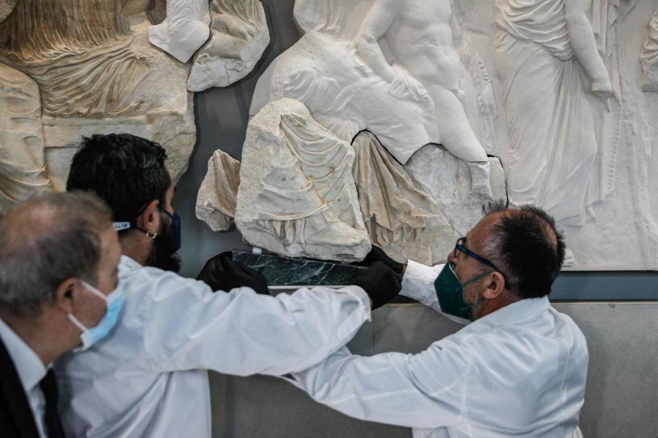 Acropolis museum staff members display a marble fragment from the Parthenon, believed to depict the foot and lower tunic of the goddess Artemis, in Athens on January 10, 2022. - The marble will be displayed at the Acropolis Museum for the next eight years following an agreement with the Antonino Salinas Museum in Palermo, Sicily.

Parts of the Parthenons eastern frieze depicting Greek gods watching a sacred procession,  were formerly in the collection of 19th century British diplomat Robert Fagan before being purchased by the University of Palermo after 1818.