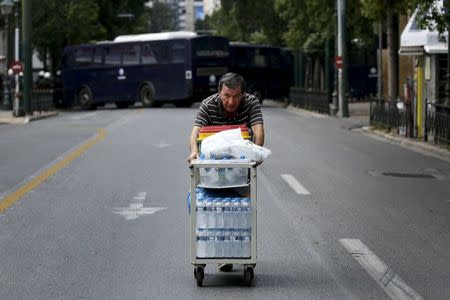 A man pushes a trolley with bottles of drinking water for sale on a deserted street during demonstrations in Athens, Greece, June 30, 2015. REUTERS/Yannis Behrakis