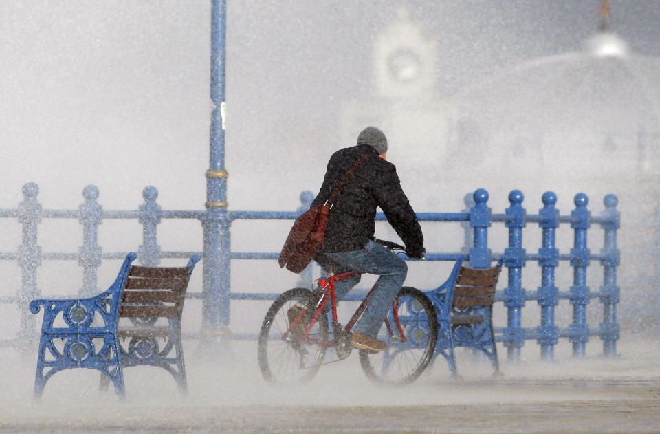 A man rides a bicycle as waves hit the sea wall in Porthcall, south Wales, March 10, 2008. A storm rushing in from the Atlantic lashed the south west on Monday as high winds and tides brought the risk of coastal flooding.     REUTERS/ Eddie Keogh   (BRITAIN)