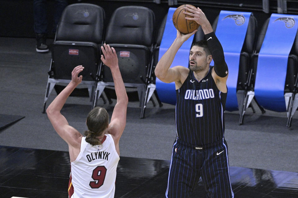 Nikola Vucevic (9) del Magic de Orlando dispara al aro frente a Kelly Olynyk (9) del Heat de Miami, el domingo 14 de marzo de 2021, en Orlando. (AP Foto/Phelan M. Ebenhack)