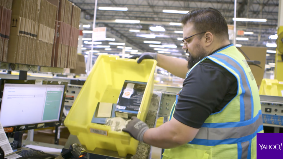 An Amazon fulfillment center worker getting ready to package a customer’s order. Source: Yahoo Finance