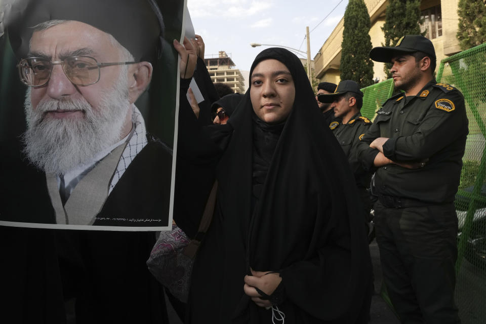 A protester holds a portrait of the Iranian Supreme Leader Ayatollah Ali Khamenei during a protest against Sweden in front of the Swedish Embassy as police officers stand guard, in Tehran, Iran, Friday, July 21, 2023. Thousands of people took to the streets in a handful of Muslim-majority countries Friday to express their outrage at the desecration of a copy of the Quran in Sweden, a day after protesters stormed the country's embassy in Iraq. (AP Photo/Vahid Salemi)