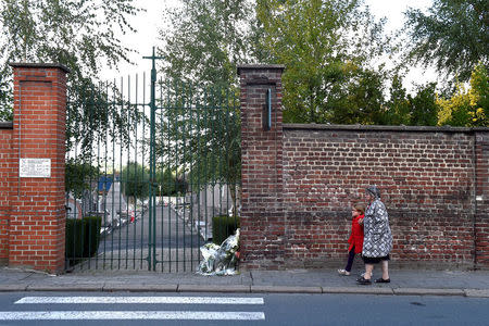 An old woman and a child walk outside the cemetery where the Belgian mayor Alfred Gadenne was found dead in Mouscron, Belgium September 12, 2017. REUTERS/Eric Vidal