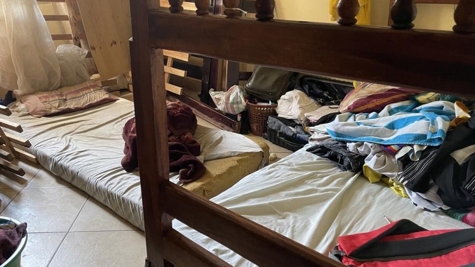 Dormitorio con ropa en el suelo.