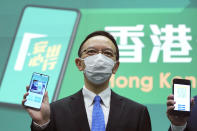 FILE - Government Chief Information Officer Victor Lam holds a mobile phone to unveil a new COVID-19 tracking health code mobile app during a news conference in Hong Kong, Thursday, Dec. 2, 2021. (AP Photo/Kin Cheung, File)