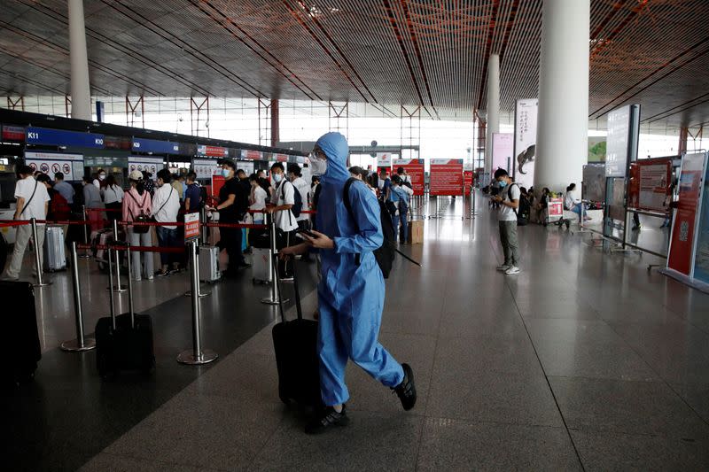 Traveler wearing protective gear walks with luggage at the departure hall of Beijing Capital International Airport