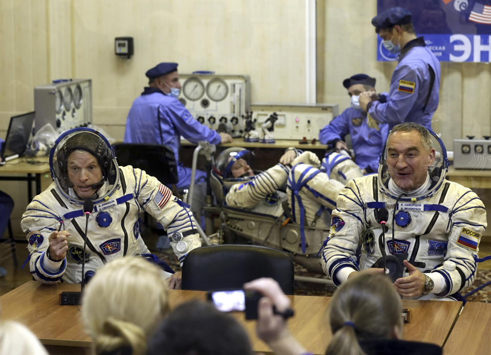 FILE - In this Tuesday, March 25, 2014 file photo, U.S. astronaut Steven Swanson, left, and Russian cosmonaut Alexander Skvortsov, crew members of the mission to the International Space Station, speak with relatives during pre-launch preparations at the Russian-leased Baikonur cosmodrome in Kazakhstan. Cosmonaut Oleg Artemyev is at center background. In an announcement Wednesday, April 2, 2014, NASA says it is suspending its work with Russia except for the International Space Station. The move comes a week after the space agency said U.S.-Russian space relations were fine despite Russia's annexation of the Crimean Peninsula from Ukraine. NASA employees are barred from traveling to Russia until further notice. Workers also can't email or hold teleconferences with their Russian counterparts. (AP Photo/Maxim Shipenkov, Pool, File)