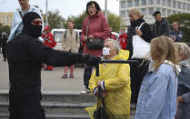 Women argue with a police officer during an opposition rally to protest the official presidential election results in Minsk, Belarus, Sunday, Sept. 27, 2020. Tens of thousands of demonstrators marched in the Belarusian capital calling for the authoritarian president's ouster, some wearing cardboard crowns to ridicule him, on Sunday as the protests that have rocked the country marked their 50th consecutive day. (AP Photo/TUT.by)
