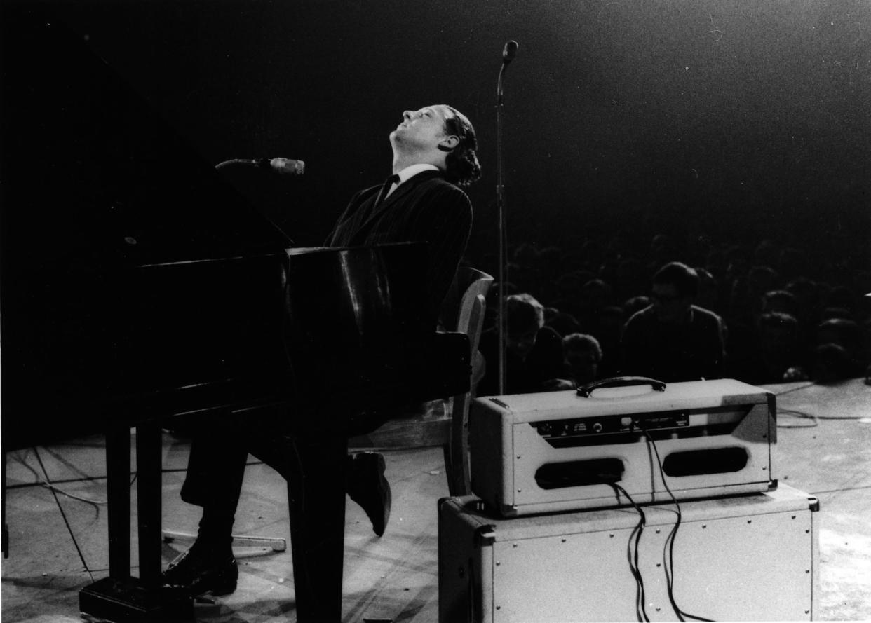 Jerry Lee Lewis performs on stage, singing into two microphones, at the Deutschlandhalle in 1963 in Berlin.