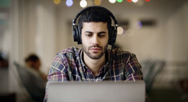 Businessman wearing headphones while working late on laptop in creative office