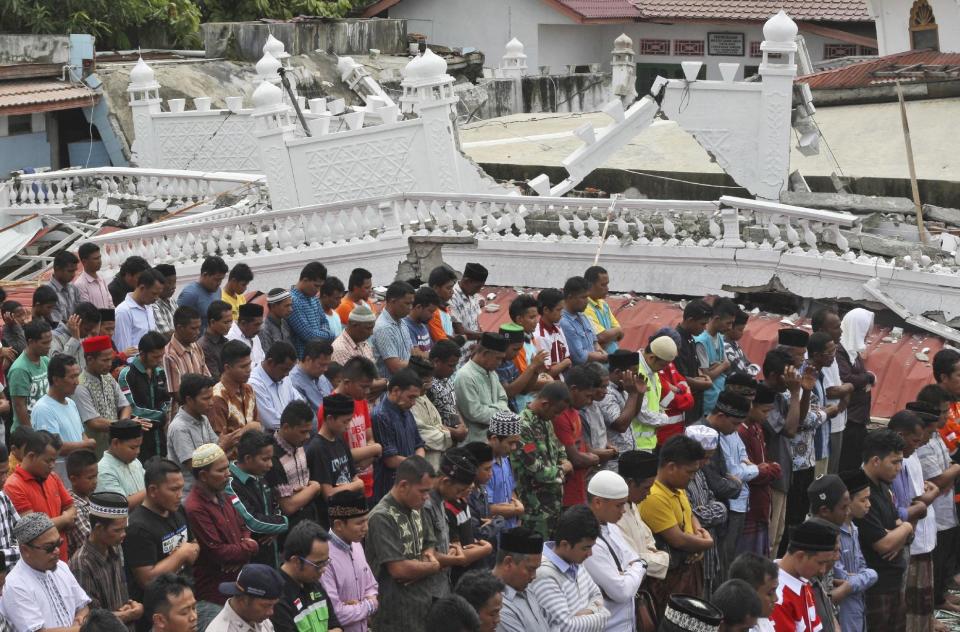 Survivors perform Friday prayer at a Jami Quba mosque which was severely damaged during Wednesday's earthquake in Tringgading, Aceh province, Indonesia, Friday, Dec. 9, 2016. Over one hundred people were killed in the quake that hit the northeast of the province on Sumatra before dawn Wednesday. Hundreds of people were injured and thousands buildings destroyed or heavily damaged. (AP Photo/Binsar Bakkara)
