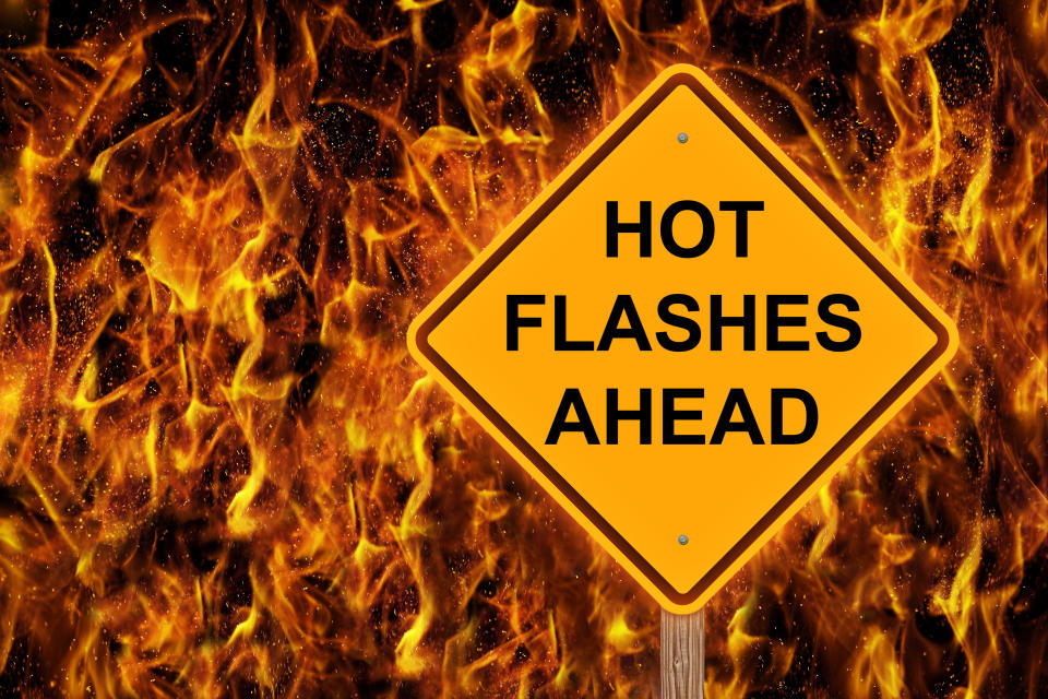 road sign saying hot flashes ahead with flames in the background