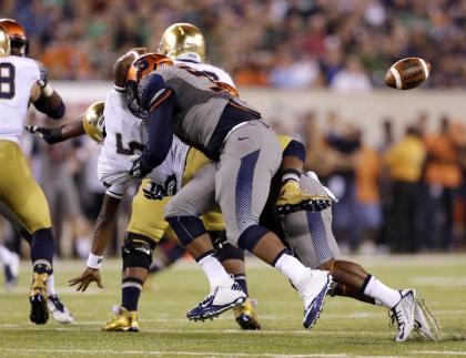 Notre Dame quarterback Everett Golson (5) loses the ball after being hit by Syracuse defensive end Isaiah Johnson, front, and linebacker Cameron Lynch during the first half of an NCAA college football game, Saturday, Sept. 27, 2014, in East Rutherford, N.J. (AP Photo/Julio Cortez)