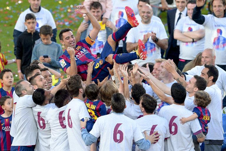 Barcelona's midfielder Xavi Hernandez is tossed by teammates as they celebrate their Spanish league title at the Camp Nou stadium in Barcelona on May 23, 2015