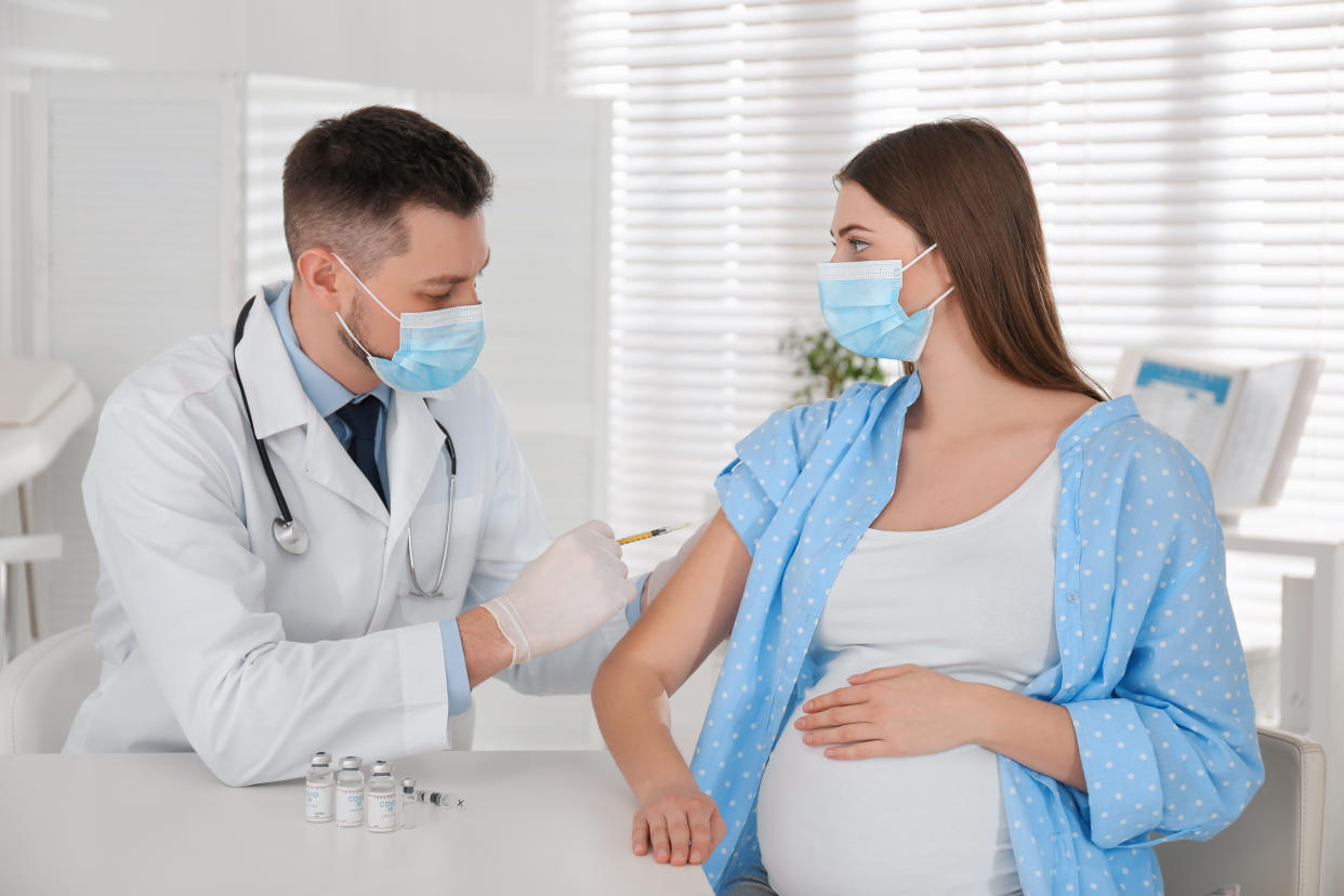 Doctor vaccinating pregnant woman against Covid-19 in clinic