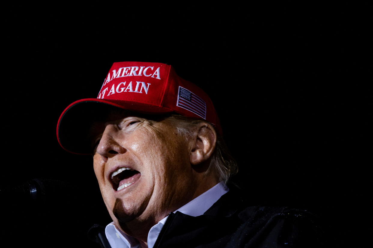 Donald Trump, in red MAGA baseball cap, speaks at a rally 
