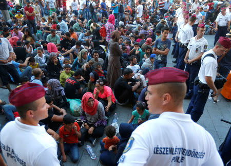 FILE PHOTO: Hungarian police officers watch migrants outside the main Eastern Railway station in Budapest, Hungary, September 1, 2015. REUTERS/Laszlo Balogh/File Photo