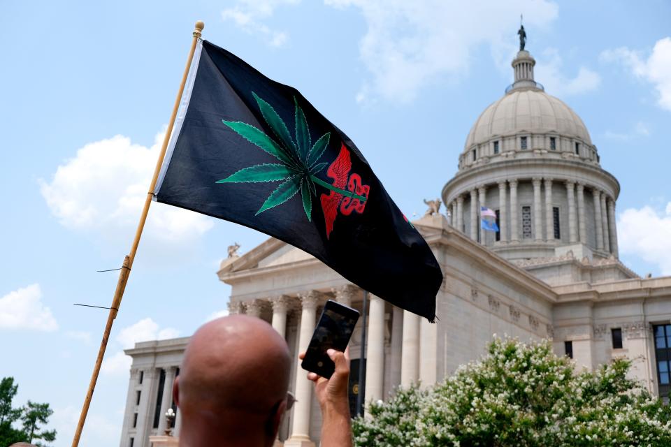 A man takes a photo of a medical marijuana flag in front of the state Capitol. Supporters of medical marijuana rally July 30, 2021, at the Capitol in support of better transparency from the Oklahoma Medical Marijuana Authority (OMMA).