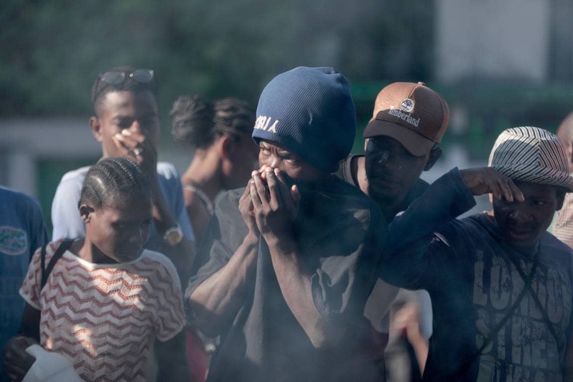 Bystanders look at the bodies of alleged gang members that were set on fire by a mob after they were stopped by police while traveling in a vehicle in the Canape Vert area of Port-au-Prince, Haiti, Monday, April 24, 2023.