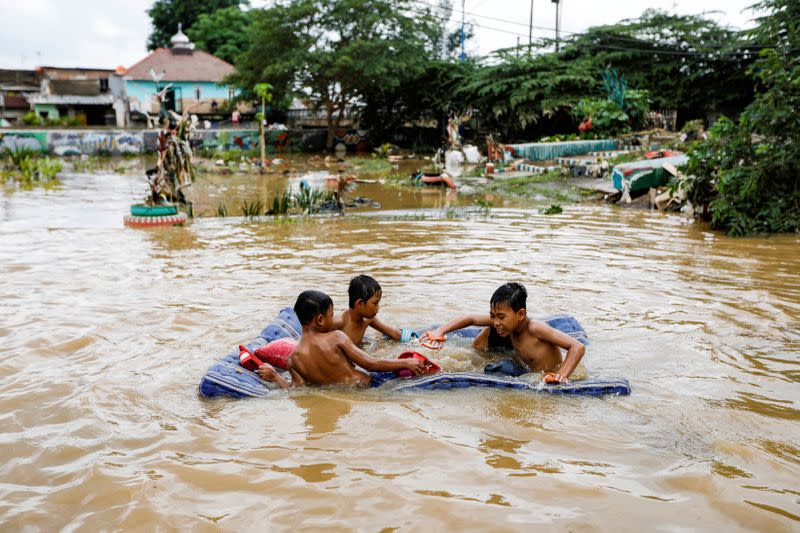 Children play in the floodwaters at the Jatinegara area after heavy rains in Jakarta