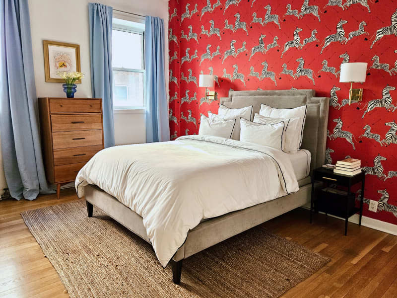 white bedroom with red zebra wallpaper accent wall and light blue curtains