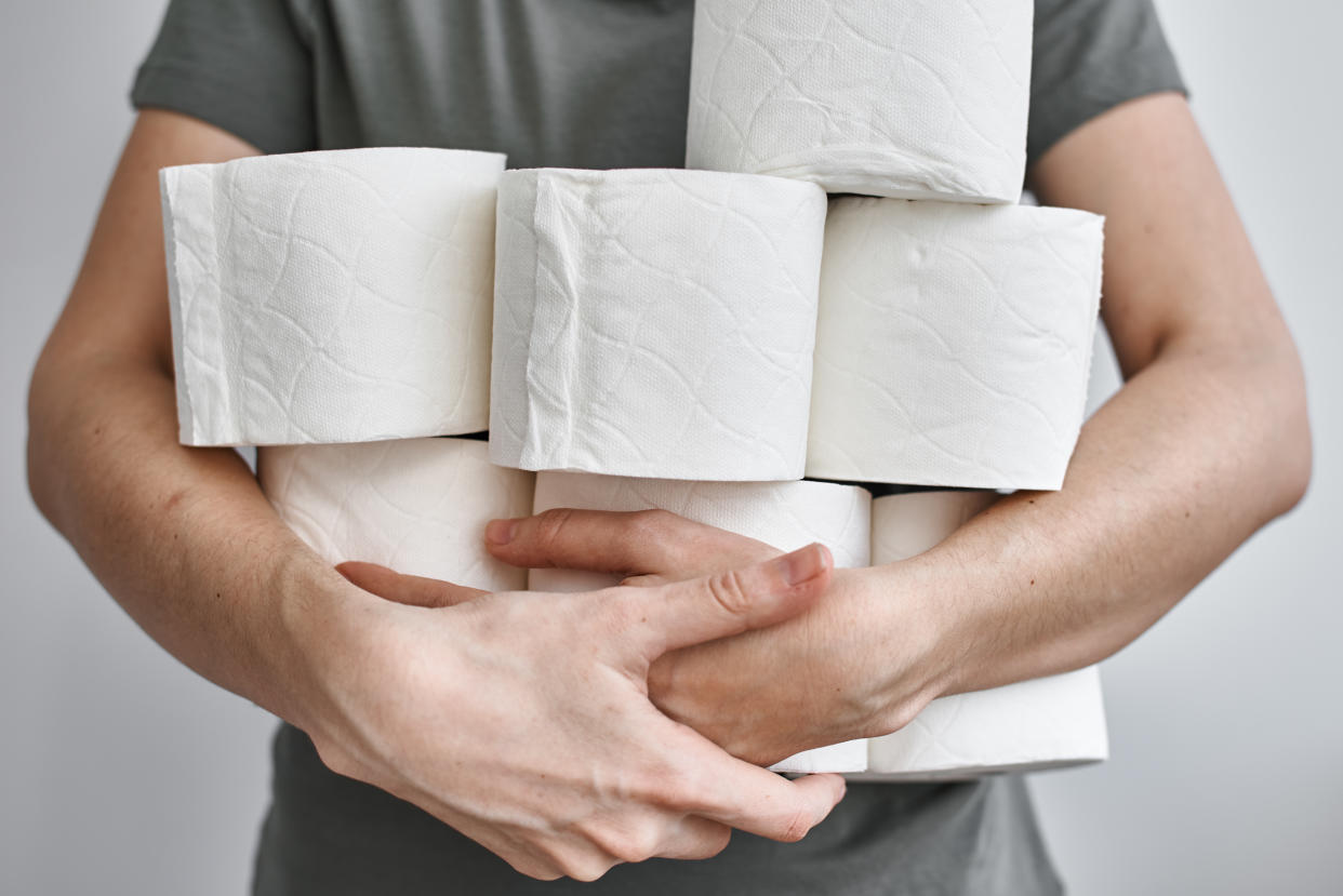 People are stocking up toilet paper for home quarantine from crownavirus. Woman holds many rolls of toilet paper