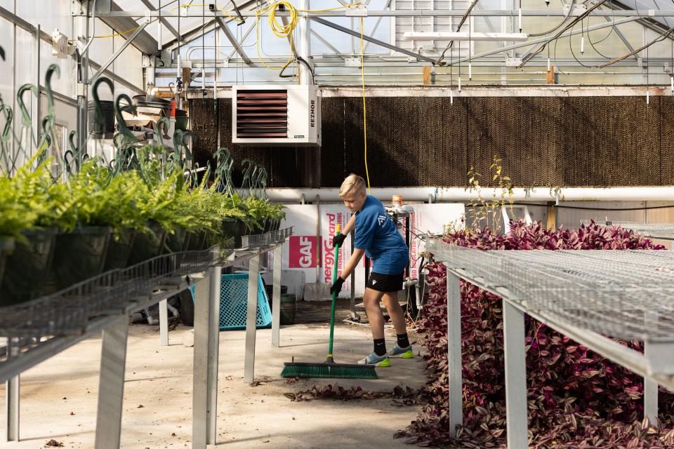 A Hands On Nashville volunteer sweeps leaves in a greenhouse. The organization partners with nonprofits in Middle Tennessee to connect people with volunteer opportunities.