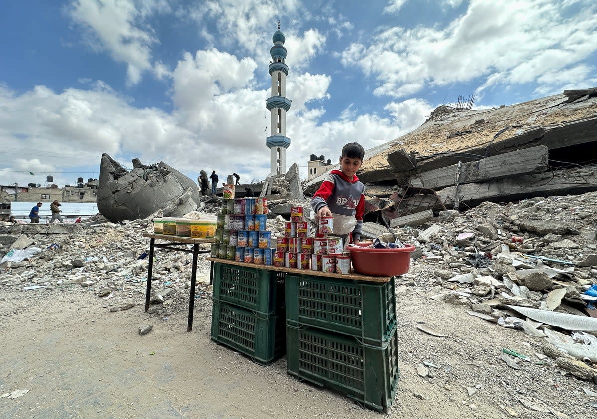 A boy stands next to canned food in Rafah in the south of Gaza on 22 March (REUTERS)