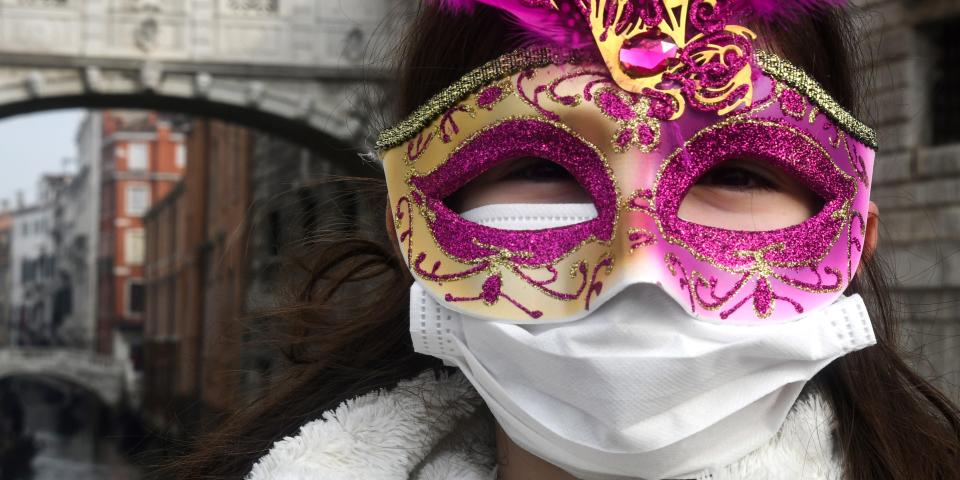 A young tourist wearing a protective facemask and a Carnival mask visits the streets of Venice, on February 24, 2020 during the usual period of the Carnival festivities which the last two days have been cancelled due to an outbreak of the COVID-19 the novel coronavirus, in northern Italy. - Italy reported on February 24, 2020 its fourth death from the new coronavirus, an 84-year old man in the northern Lombardy region, as the number of people contracting the virus continued to mount. (Photo by ANDREA PATTARO / AFP) (Photo by ANDREA PATTARO/AFP via Getty Images)