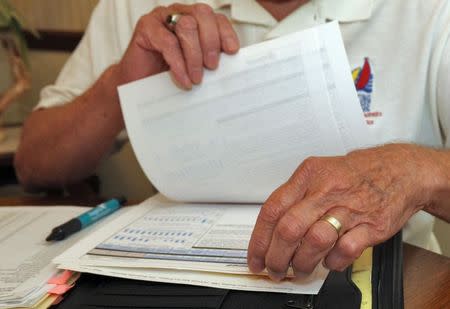 Retired engineer Bill Jenkins looks over documents concerning his investment in Reef's Income & Development Fund II at his home in Orlando, Florida, October 31, 2014. REUTERS/Steve Nesius