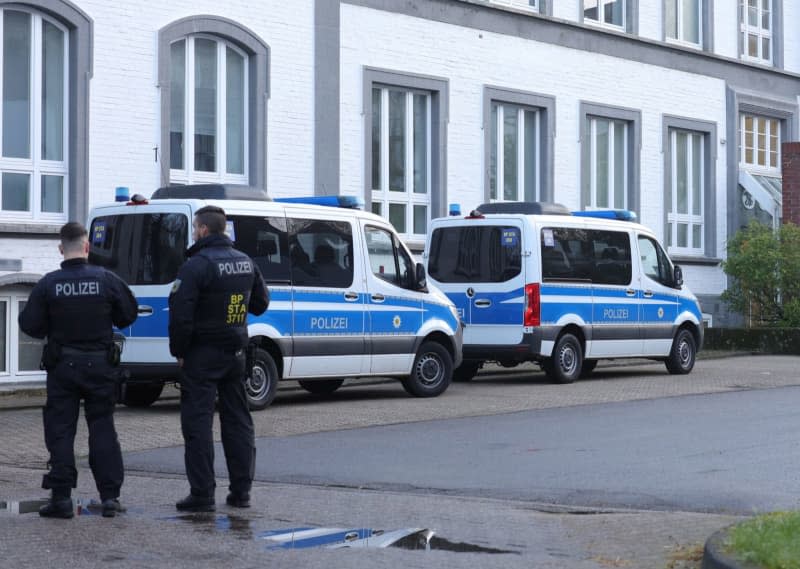 Police officers stand near a building that is being searched during a large-scale raid against an international smuggling gang in eight states. Gianni Gattus/dpa