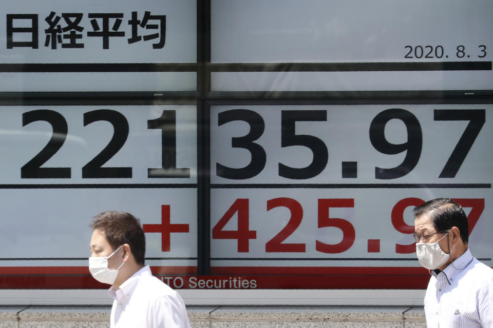 People wearing face masks walk by an electronic stock board of a securities firm in Tokyo, Monday, Aug. 3, 2020. Asian shares were mixed on Monday, as investors watched surging numbers of new coronavirus cases in the region, including in Japan. (AP Photo/Koji Sasahara)