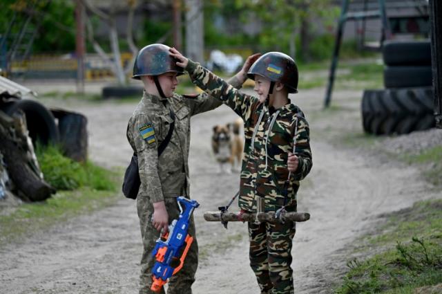 Maksym (g) et son ami Valentyn jouent à la guerre dans le village de Stoïanka, près de Kiev, le 11 mai 2023 en Ukraine