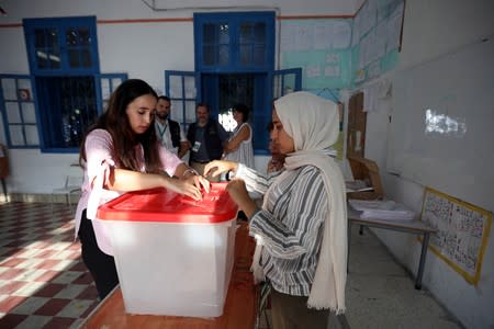 Electoral workers prepare a ballot box inside a polling station during presidential election in Tunis