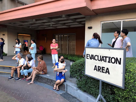 Residents sit outside after being evacuated from the condominium building after an earthquake in Makati City, Philippines, April 22, 2019. REUTERS/Martin Petty