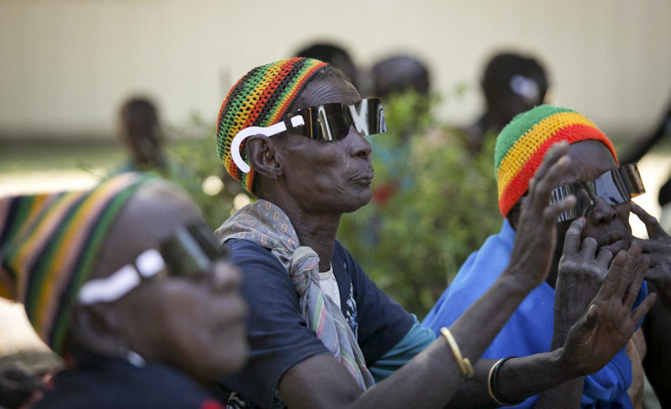 In this photo taken Dec. 16, 2012 and released by the Moran Eye Center, a woman from the Dinka tribe sings and dances with members of the Nuer tribe after their sight was restored by eye surgeons from the John A. Moran Eye Center of the University of Utah, in the village of Duk Payuel in Jonglei state, South Sudan. South Sudan's government faces monumental challenges: To bring warring factions, often from rival ethnic groups, back toward peace after violence broke out across the country on Dec. 15, but a group of American doctors has a unique approach to help heal age-old rifts between the ethnic groups, eye surgery, although it has been put on hold because of the fighting. (AP Photo/Moran Eye Center, Patrick Reddish)