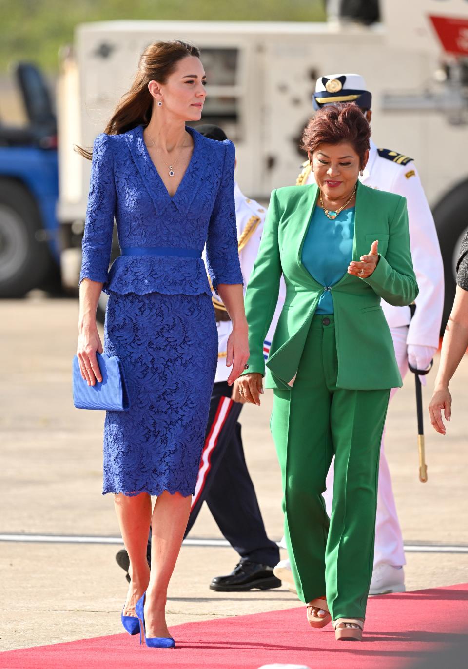 Kate in a bright blue v neck peplum lace top with a patching pencil skirt. She also holds a blue clutch and matching heels.