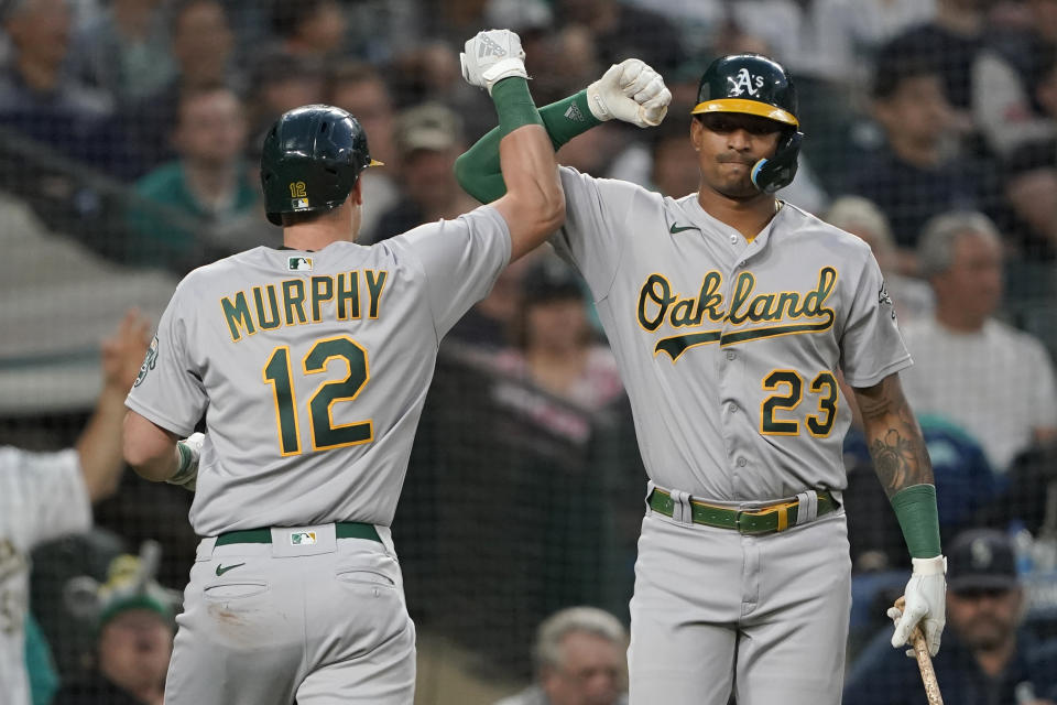 Oakland Athletics' Sean Murphy (12) is congratulated by Christian Bethancourt (23) after Murphy hit a solo home run against the Seattle Mariners during the seventh inning of a baseball game Friday, July 1, 2022, in Seattle. (AP Photo/Ted S. Warren)