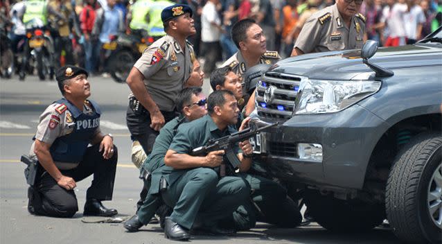 Indonesian police take position behind a vehicle as they pursue suspects. Photo: Getty Images