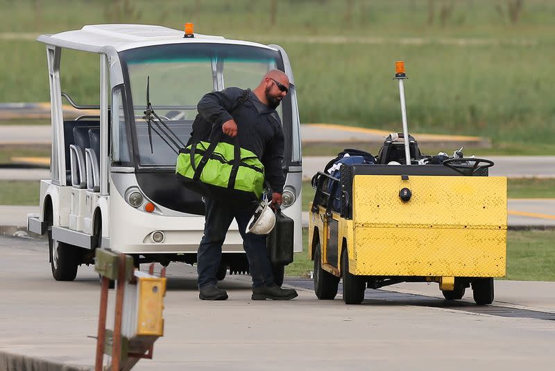 A worker carries his bags while disembarking from a helicopter after being evacuated from oil production platforms ahead of Tropical Storm Cristobal in Galliano