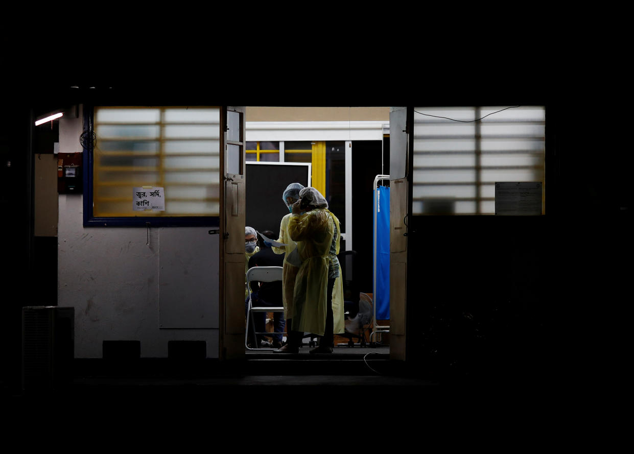 A doctor attends to a migrant worker with coronavirus symptoms at HealthServe clinic here on 8 April, 2020. The worker was later sent to a hospital in an ambulance. (PHOTO: Reuters)